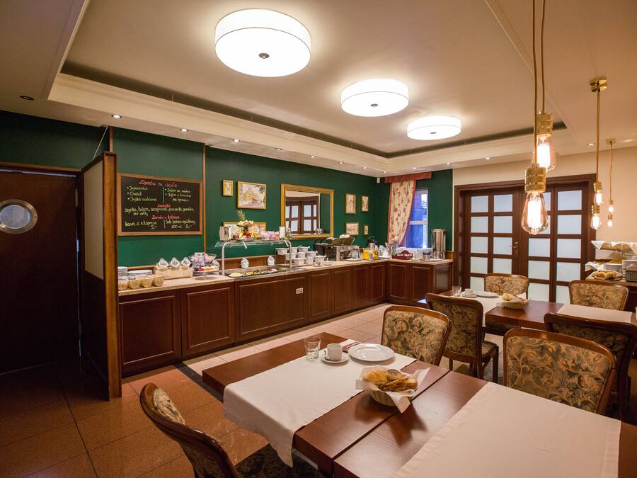 Un restaurante con barra libre, mobiliario de madera y una pared verde con un menú.