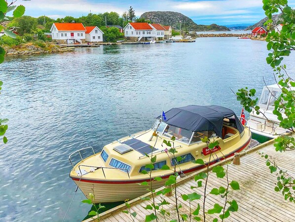 A boat docked at a pier with a view of houses and a mountain in the background. - 4 Person Holiday Home in Lyngdal (Lyngdal)