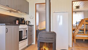 A compact kitchen with a wood-burning stove, a coffee maker, and a kettle. - 4 Person Holiday Home in Lyngdal (Lyngdal)