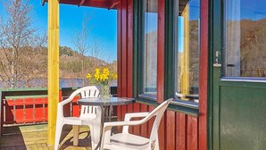 A wooden deck with a table and chairs, a vase with flowers, and a view of the landscape. - 4 Person Holiday Home in Lyngdal (Lyngdal)