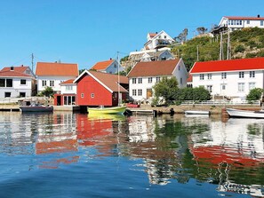 En hamn med båtar, en röd byggnad och vita hus med röda tak.