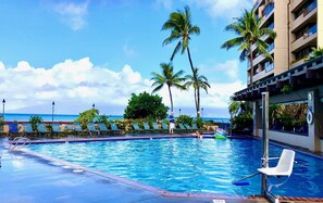 Une piscine dotée de chaises longues, de palmiers et offrant une vue sur l’océan.