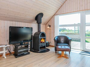 Une pièce avec un poêle à bois, une télévision et un fauteuil en cuir.