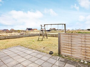 Une terrasse dallée avec une balançoire en bois et une échelle.