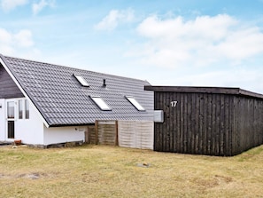 Une maison avec un toit en pente, une clôture en bois et une plaque portant le numéro 17.