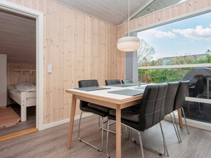 A modern room with a wooden interior, a dining table with chairs, and a large window offering a view of greenery. - 6 Person Holiday Home in Bjert-by Traum (Bjert)
