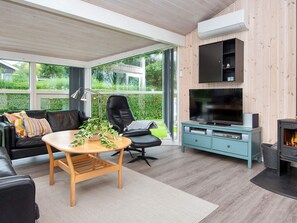 A modern living room with a sofa, a table, a chair, a television, and a fireplace. - 6 Person Holiday Home in Bjert-by Traum (Bjert)