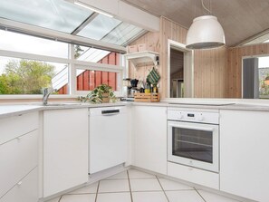 A modern kitchen with a built-in oven, a dishwasher, and a window with a view of the outside. - 6 Person Holiday Home in Bjert-by Traum (Bjert)