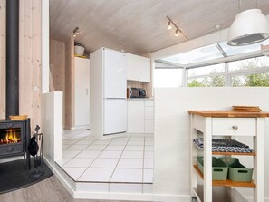 A modern kitchen with a white refrigerator, a stove with a basket on top, and a window above the sink. - 6 Person Holiday Home in Bjert-by Traum (Bjert)