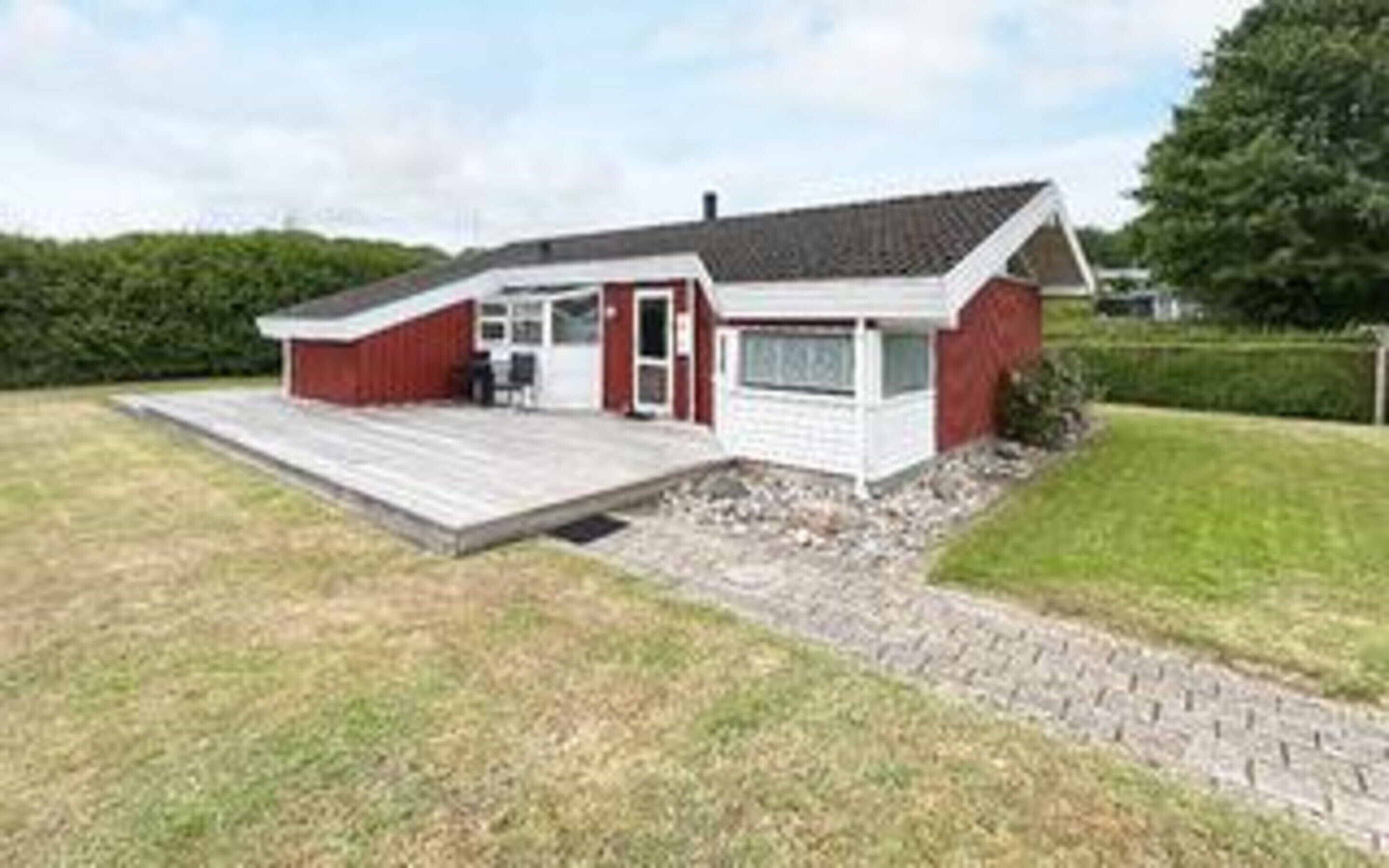 Une maison de plain-pied avec un porche à l’avant, un garage et une petite terrasse.