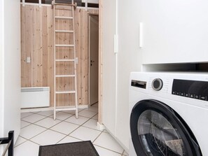 Un cuarto de lavandería con una lavadora, una puerta de madera y una escalera.