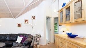 A living room with a leather sofa, wooden cabinets, and a vase with flowers. - 5 Star Holiday Home in Allingabro (Allingåbro)