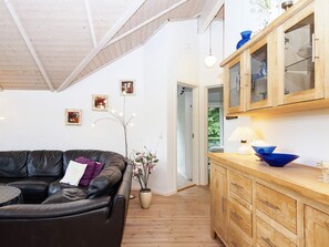 A living room with a leather sofa, wooden cabinets, and a vase with flowers. - 5 Star Holiday Home in Allingabro (Allingåbro)