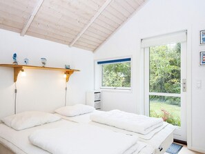 A bedroom with a bed, bedside lamps, a window, and a door leading to an outdoor area. - 5 Star Holiday Home in Allingabro (Allingåbro)