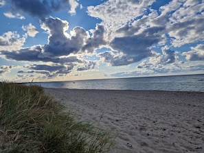 A beach with sand and grass, a body of water, and a partly cloudy sky. - 5 Star Holiday Home in Allingabro (Allingåbro)