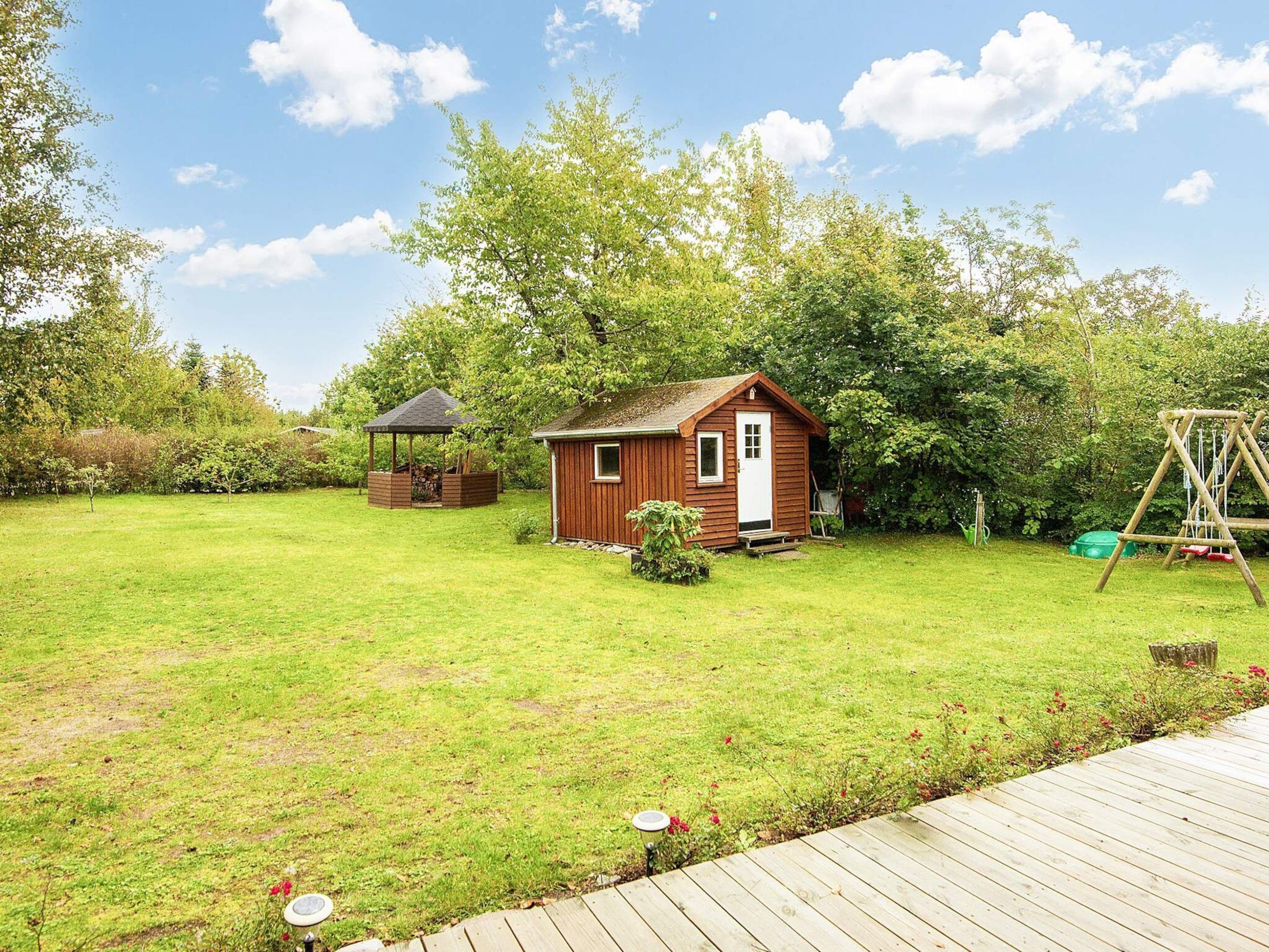 Een houten chalet met een deur en ramen, omringd door een gazon en bomen.