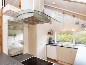 A modern kitchen with a glass cooktop, white cabinets, and a window overlooking greenery. - 5 Star Holiday Home in Allingabro (Allingåbro)