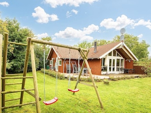 A wooden swing set in a backyard with a house in the background. - 5 Star Holiday Home in Allingabro (Allingåbro)