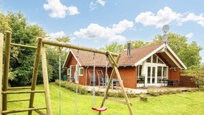 A wooden swing set in a backyard with a house in the background. - 5 Star Holiday Home in Allingabro (Allingåbro)