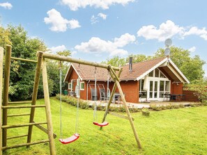 A wooden swing set in a backyard with a house in the background. - 5 Star Holiday Home in Allingabro (Allingåbro)