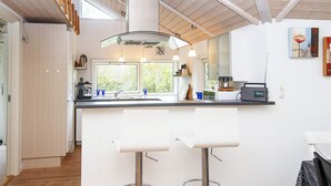 A modern kitchen with a central island, pendant lights, and a view of greenery outside. - 5 Star Holiday Home in Allingabro (Allingåbro)