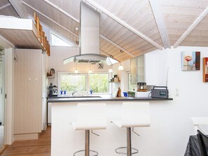 A modern kitchen with a central island, pendant lights, and a view of greenery outside. - 5 Star Holiday Home in Allingabro (Allingåbro)