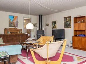 A living room with a sofa, a table with a lamp, a television, and a fireplace.