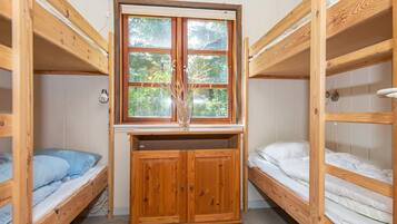 A dormitory room with bunk beds, a window, and a wooden cabinet.