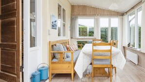A cozy room with a wooden bed, a small table, and a view of greenery outside. - Renovated Cottage Near Beach - By Traum Ferienwohnungen (Borkop)
