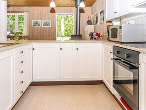 A kitchen with white cabinetry, a built-in oven, and a microwave.