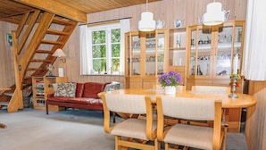 A cozy interior with a wooden dining table, cushioned chairs, a red sofa, and a staircase. - 6 Person Holiday Home in Hals (Hals)