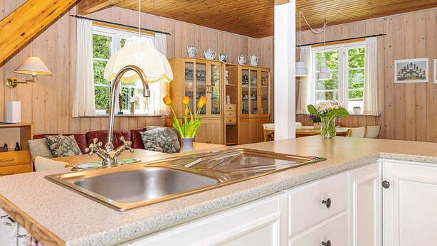 A kitchen with a sink, cabinets, and a dining area with a table and chairs. - 6 Person Holiday Home in Hals (Hals)