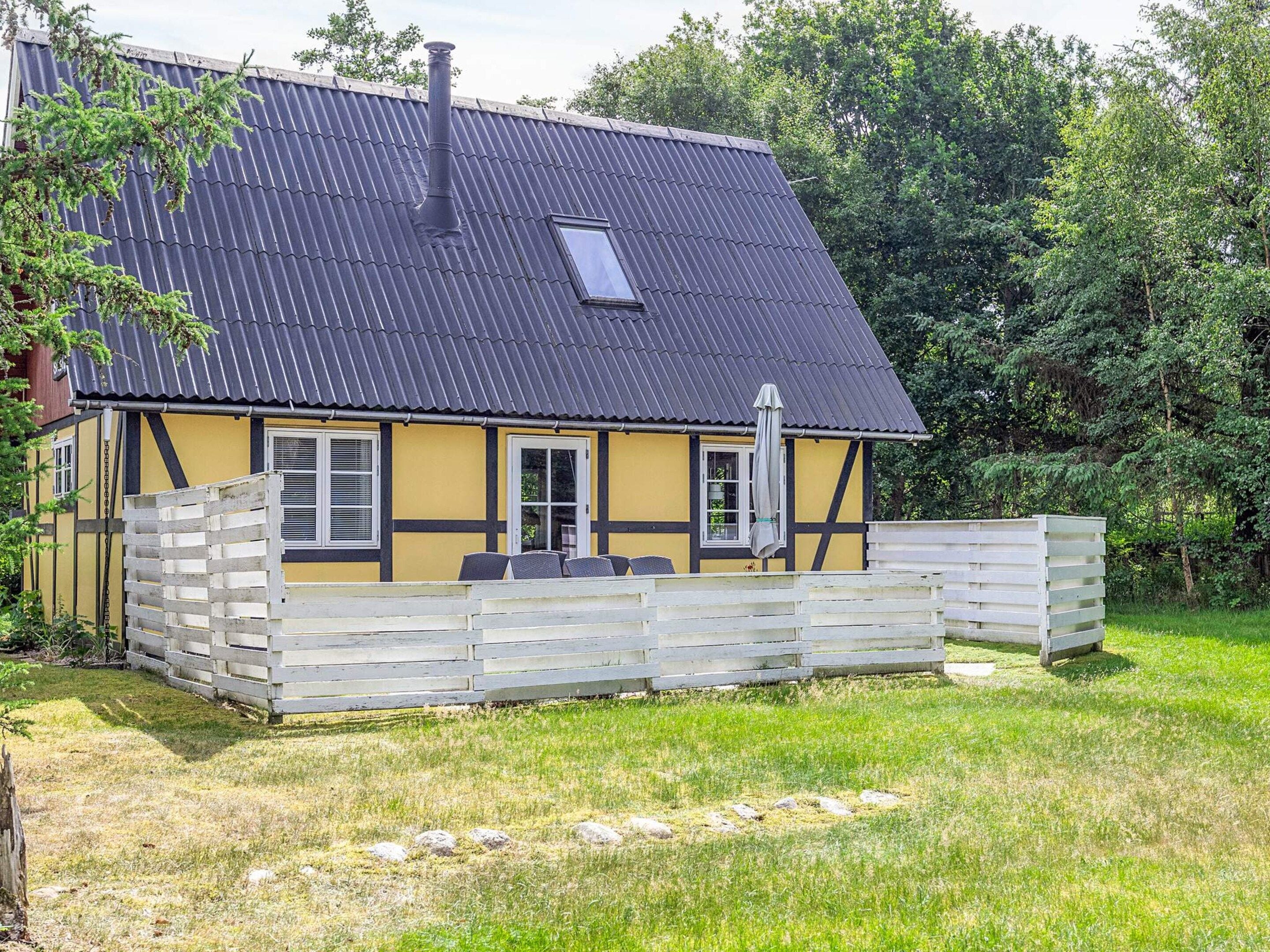 A traditional half-timbered house with a sloped roof, a chimney, and a small attached structure with outdoor seating.