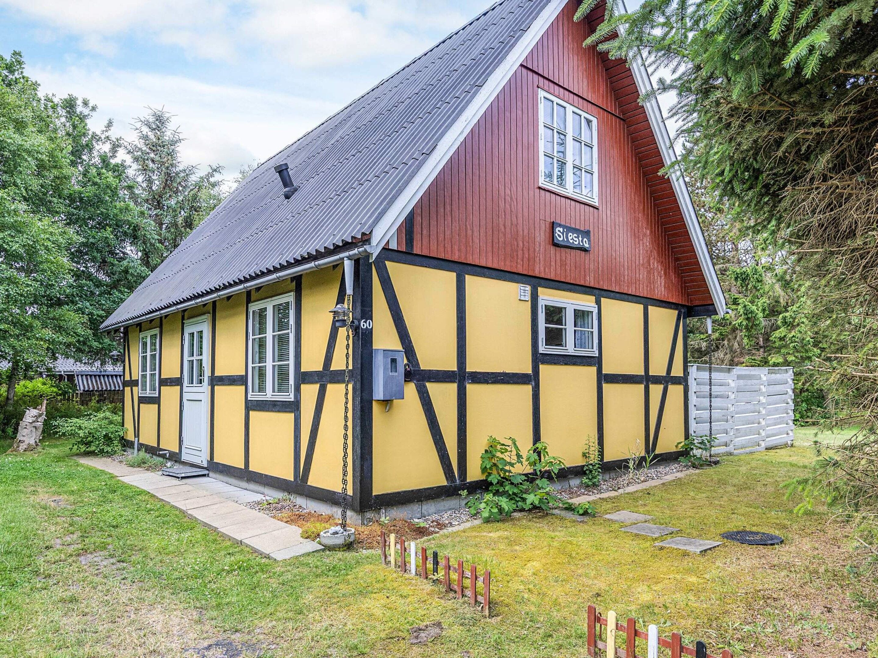 A traditional half-timbered house with a steep gable roof, a visible chimney, and a small porch.