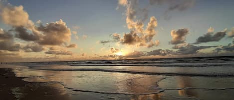 Una playa con olas y un atardecer.