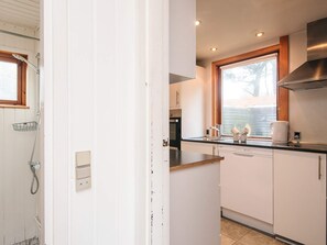 A compact kitchen with white cabinets, a stainless steel range hood, a window above the sink, and a dishwasher. - Lovely Holiday Home in Vejers Strand near Sea (Vejers Strand)