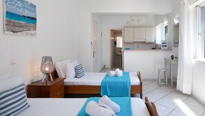 Habitación de hotel con dos camas, una kitchenette y un baño.