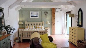 A bedroom with a bed, a dresser, a mirror, and a window.