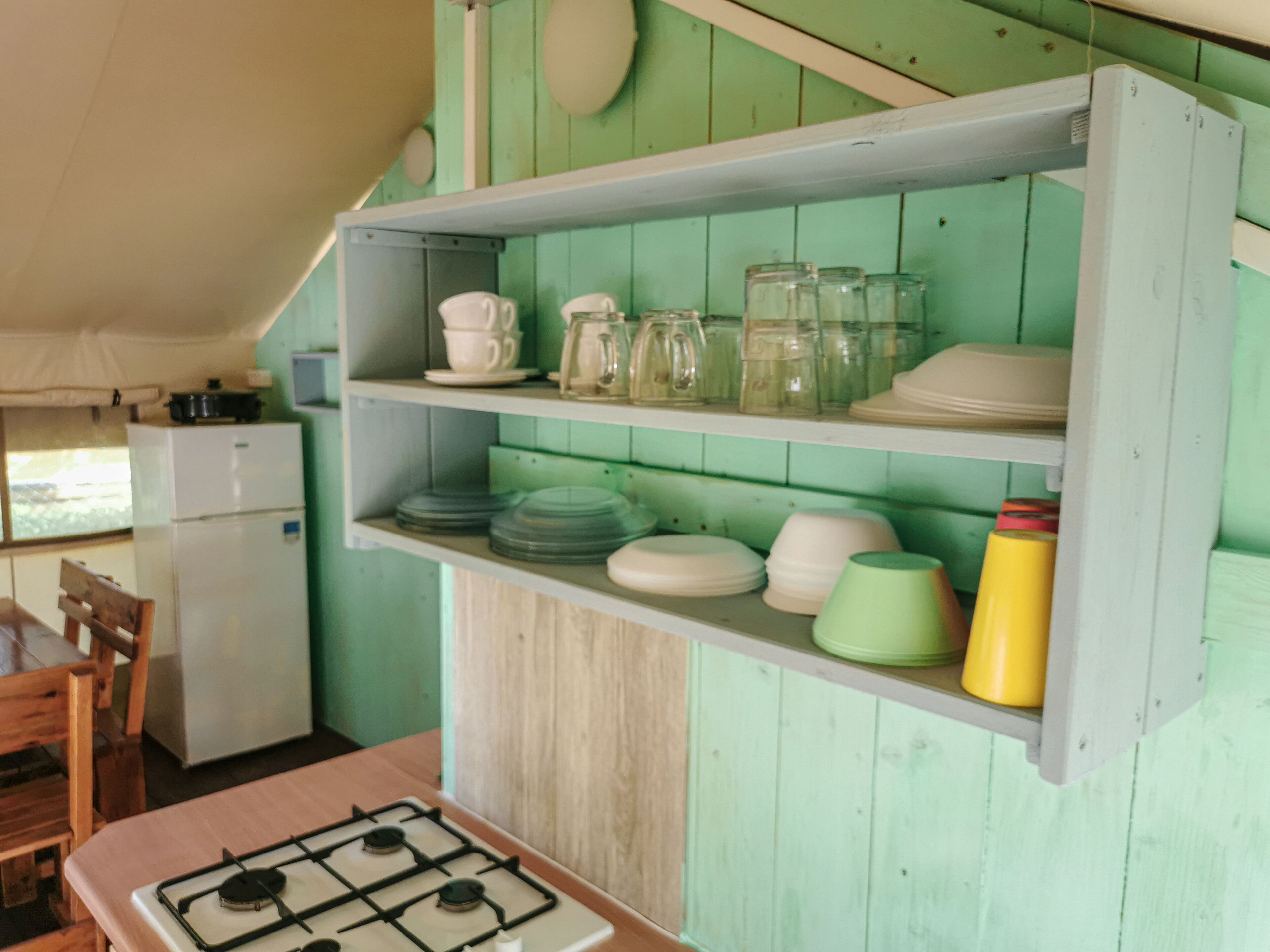 A kitchen with a gas stove, wooden cabinets, and a refrigerator.