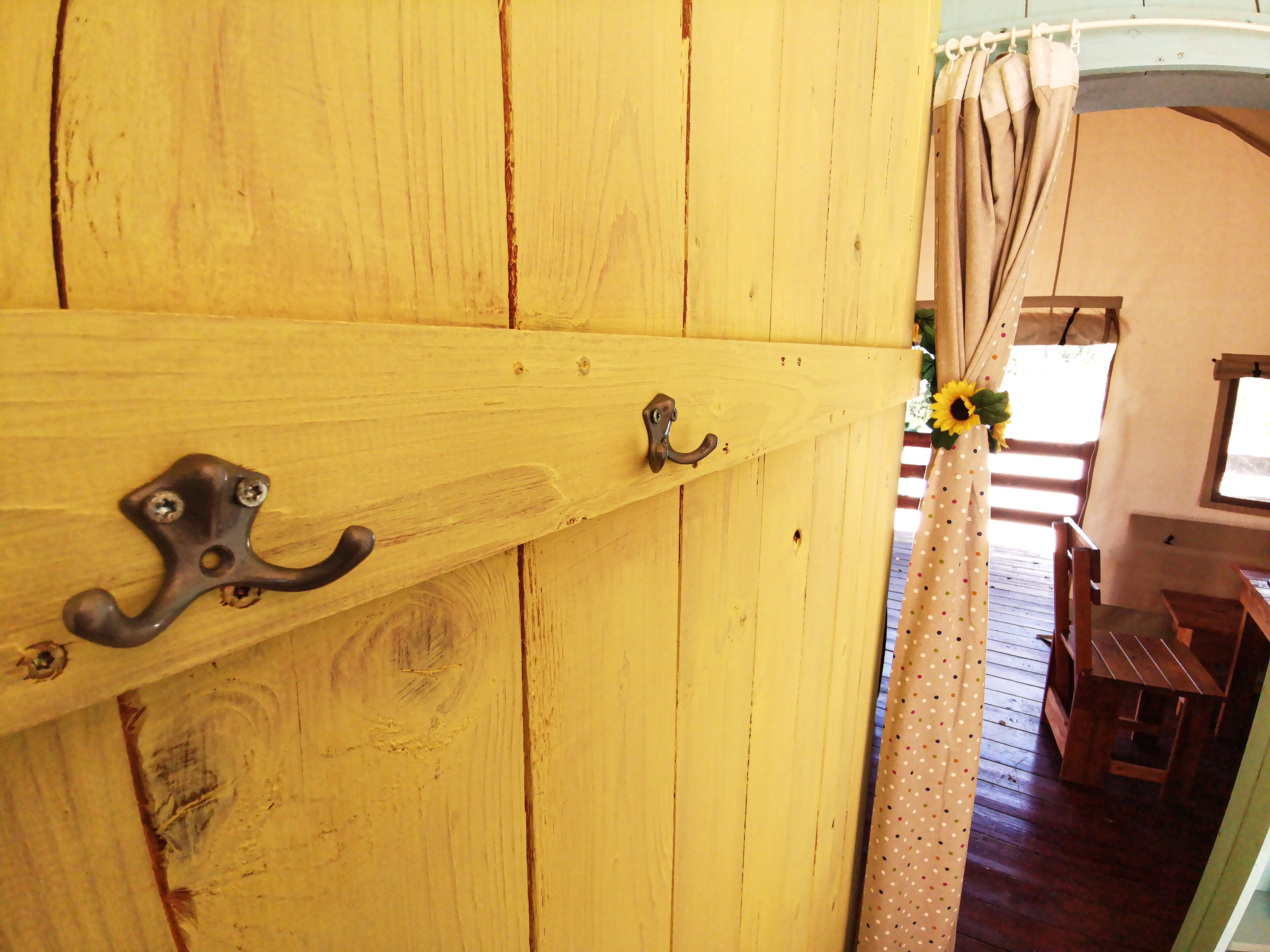 A wooden door with two metal handles and a curtain with a polka dot pattern.