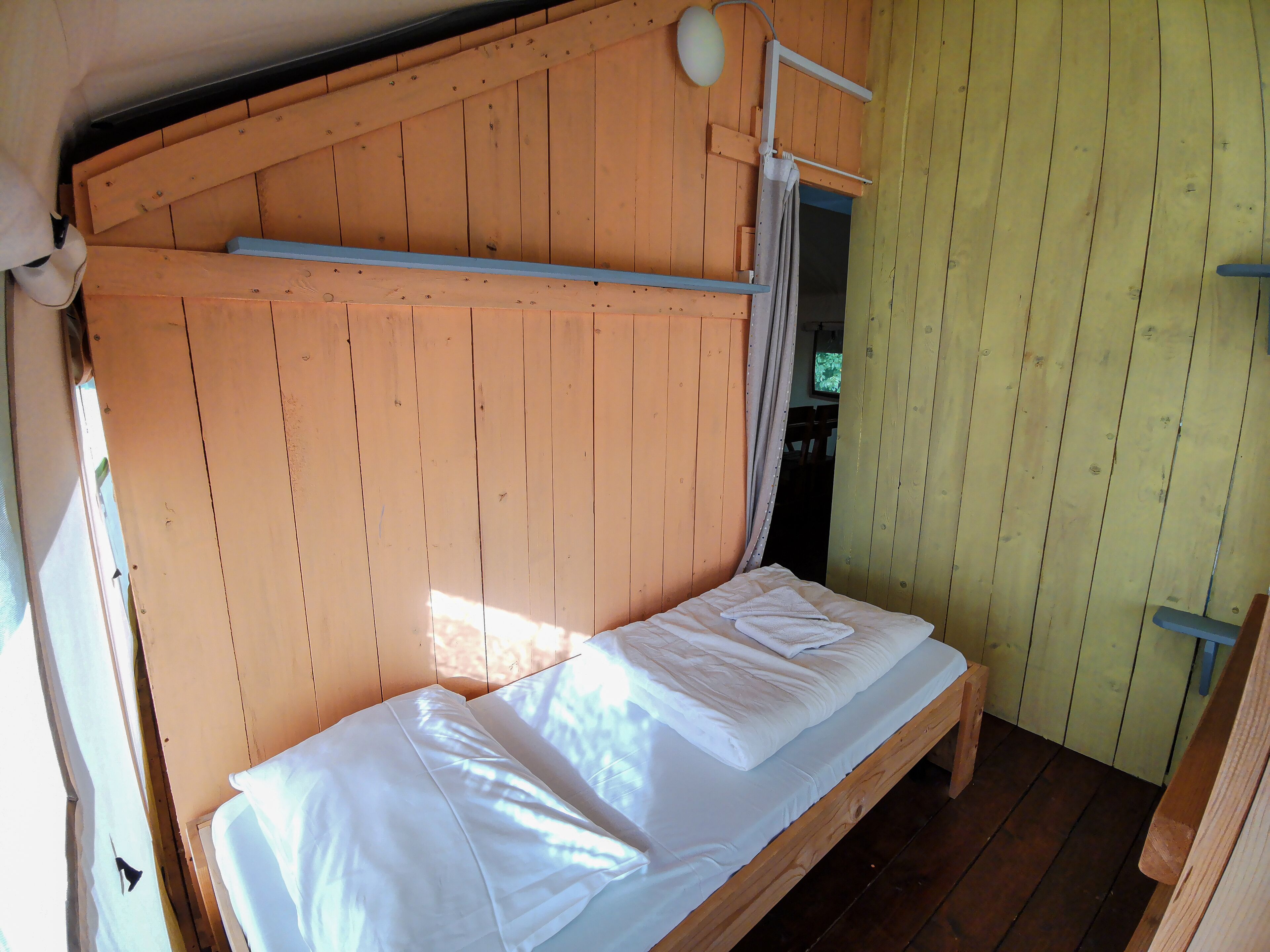 Ein Etagenbett mit Holz Kopfteil und einem kleinen Fenster.
