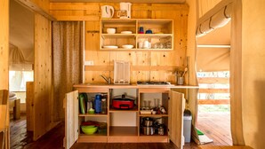 A compact wooden kitchen with shelves, a sink, and various kitchen appliances. - Sunflower Camping Savudrija (Umag)