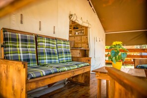 A cozy wooden bench with plaid cushions, a wooden table, and a yellow potted plant in a tent-like structure. - Sunflower Camping Savudrija (Umag)