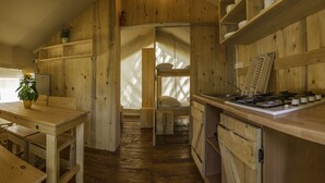A wooden interior with a kitchen area featuring a stove, shelves, and a dining table. - Sunflower Camping Savudrija (Umag)