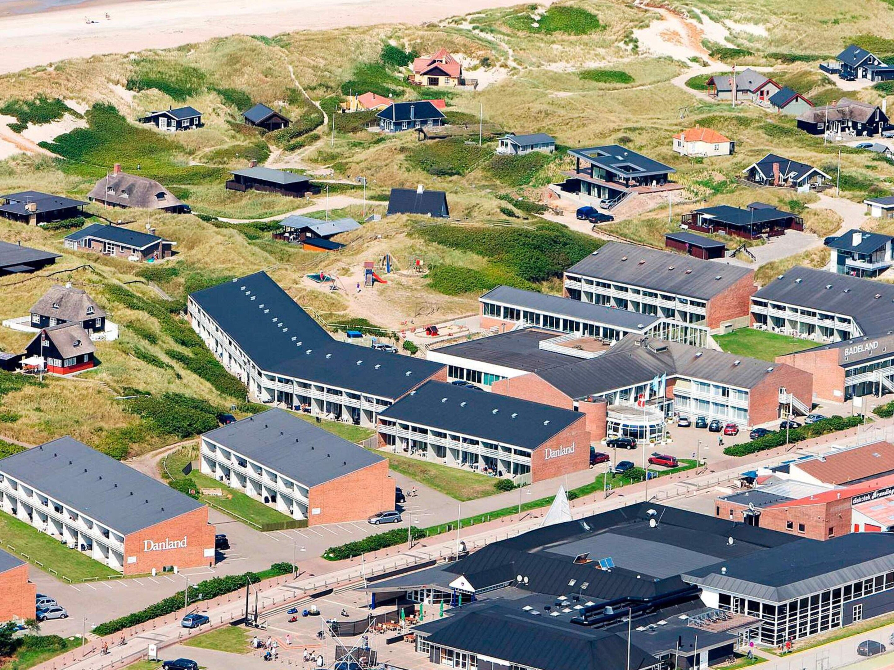 A coastal area with modern buildings, including a prominent Danland facility with a large parking lot and a beach in the background.