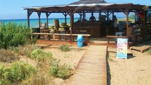 A beachside wooden structure with benches and a covered seating area, overlooking the ocean. - Irini studio for 2, central location and 5 minutes walk from the sandy beach (Corfu)