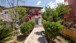 A stone pathway leading to a house with a red roof, surrounded by greenery and a fence. - Irini studio for 2, central location and 5 minutes walk from the sandy beach (Corfu)