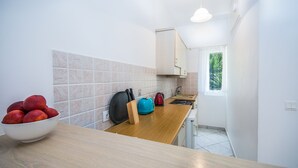 A kitchen with a wooden countertop, a bowl of fruit, a kettle, and a window with a view of greenery. - Irini studio for 2, central location and 5 minutes walk from the sandy beach (Corfu)