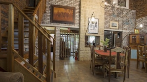 A dining area with a wooden staircase, brick walls, and a chandelier. - Doringpoort Safari Lodge (Nkomazi)