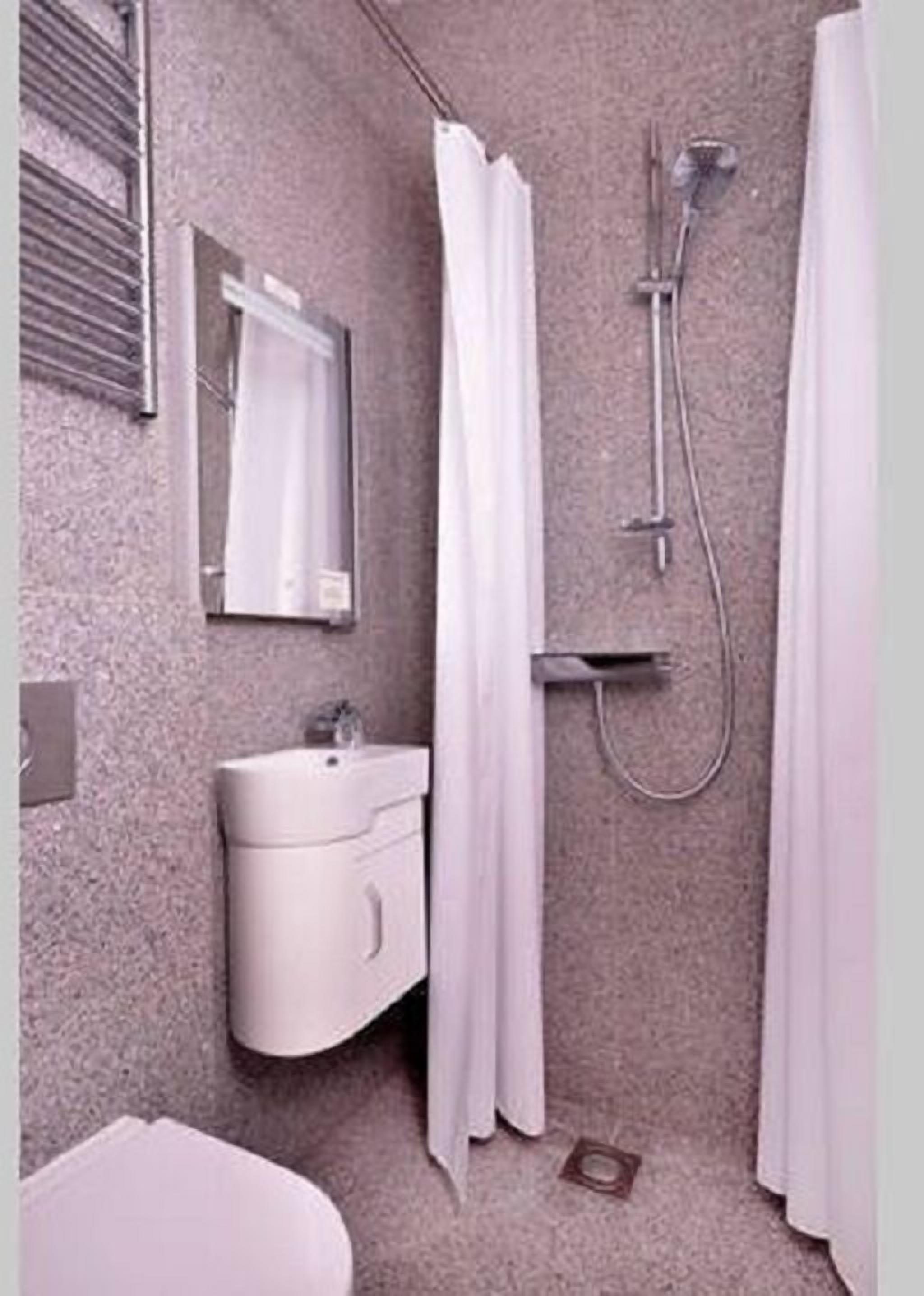 Een badkamer met wastafel, spiegel en douche.